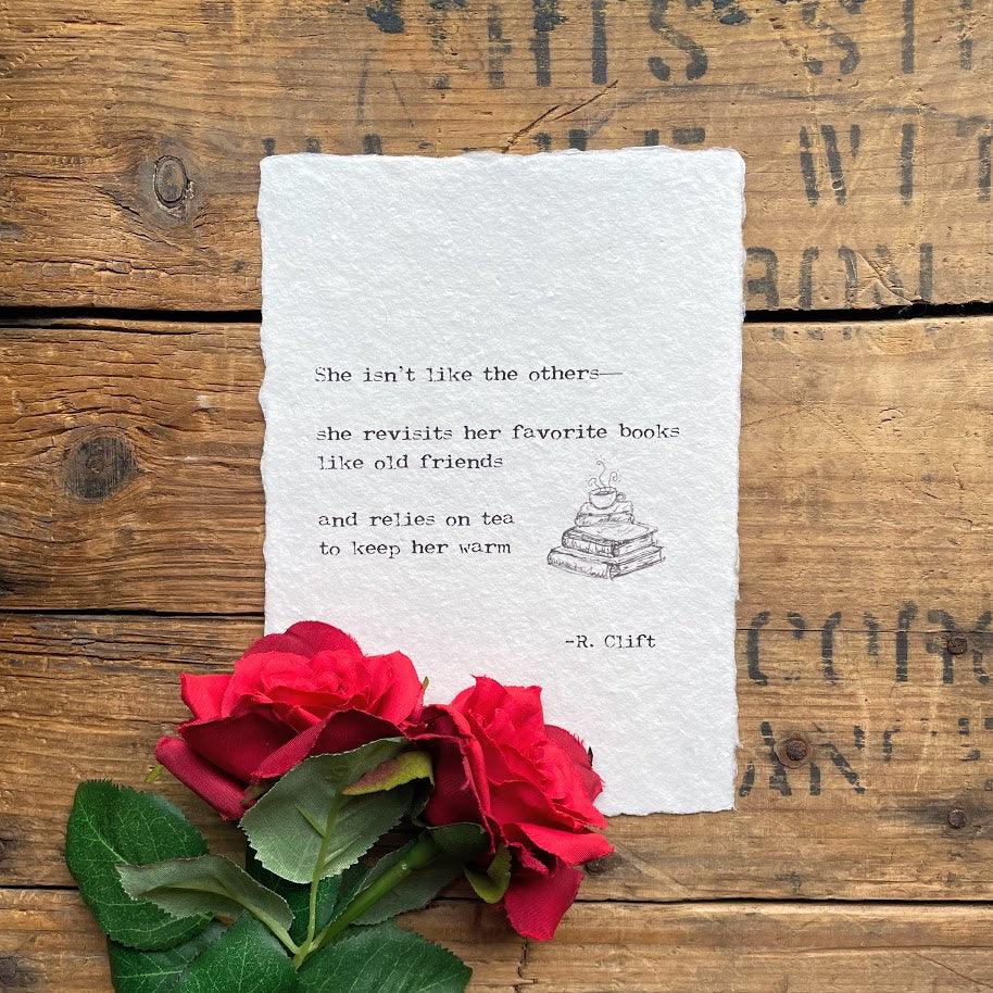 "She isn't like the others—she revisits her favorite books like old friends and relies on tea to keep her warm" poem by R. Clift with an original books and tea cup doodle, printed on handmade paper. 