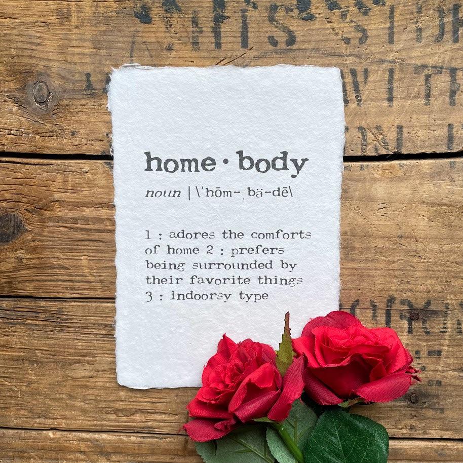 homebody definition print in typewriter font on handmade paper. What is a homebody? A homebody adores the comforts of home, prefers being surrounded by their favorite things, and is an indoorsy type.